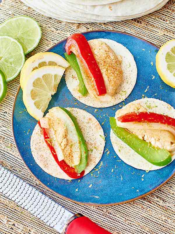 3 chicken fajitas on plate with lemon slices above