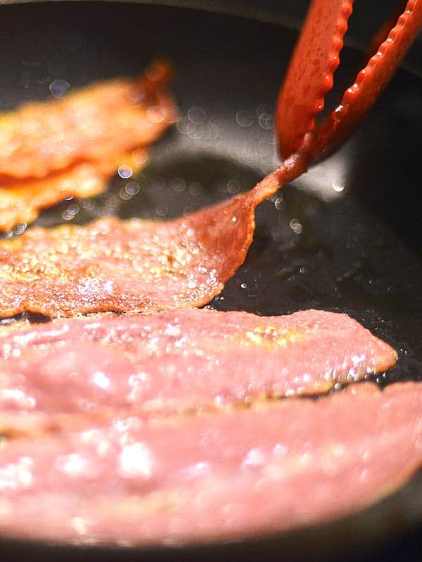 bacon being cooked in skillet