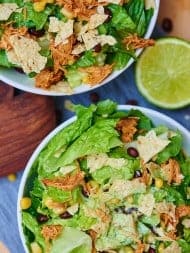 This BBQ chicken salad starts with a base of romaine, is topped with lightly salted corn and black beans, shredded chicken that's been cooking all day in the crockpot, a few crushed tortilla chips, and a Ranch yogurt dressing! Healthy, filling, and delicious! showmetheyummy.com #healthy #salad #bbq #crockpot #chicken