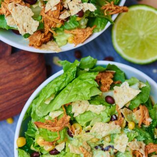 This BBQ chicken salad starts with a base of romaine, is topped with lightly salted corn and black beans, shredded chicken that's been cooking all day in the crockpot, a few crushed tortilla chips, and a Ranch yogurt dressing! Healthy, filling, and delicious! showmetheyummy.com #healthy #salad #bbq #crockpot #chicken