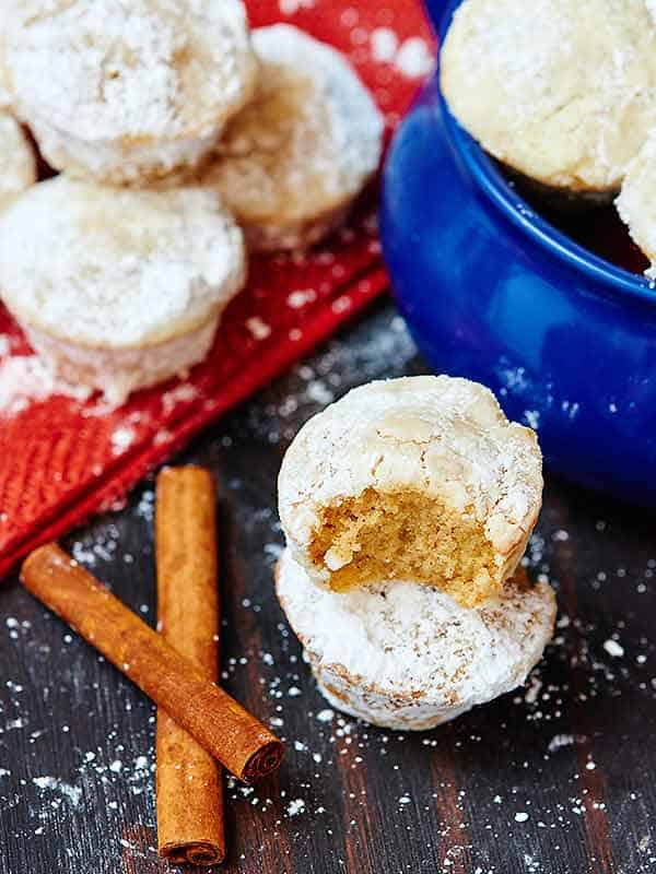 two egg nog donut muffins stacked, others stacked behind and in bowl