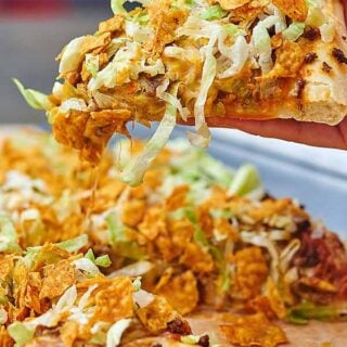 Taco Pizza. That’s right! A homemade pizza dough topped with all your favorite taco toppings…complete with beans, seasoned ground beef, two types of cheese, shredded lettuce and taco styled doritos! What could be better than pizza topped with doritos?! showmetheyummy.com #taco #pizza #tacopizza #pizzadough #homemade #easyrecipe