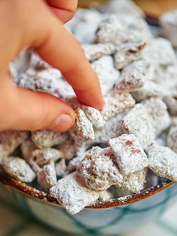 Fingers grabbing muddy buddies from bowl