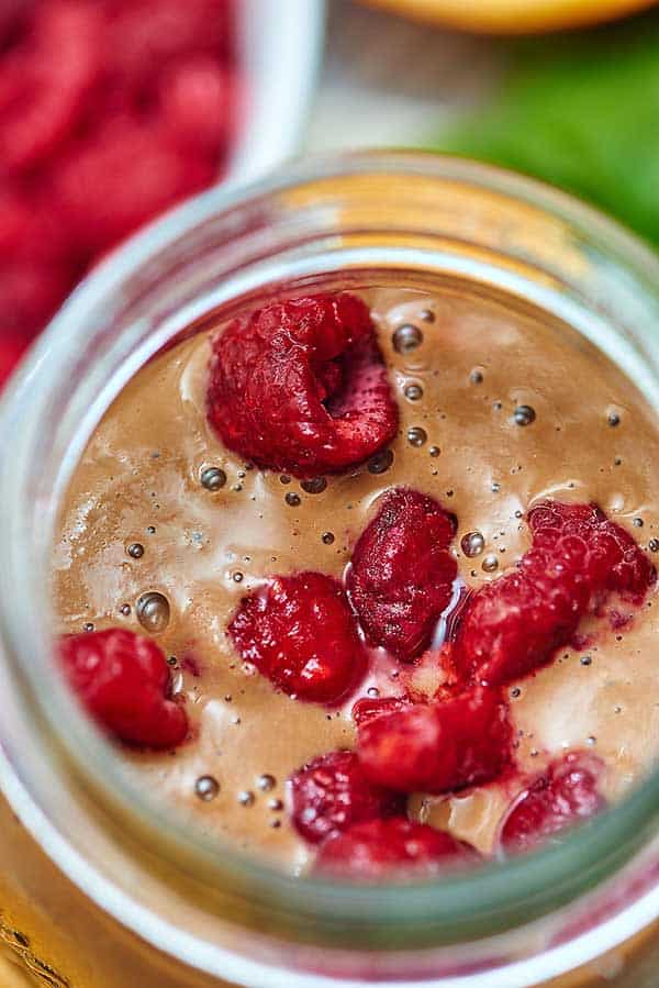 Closeup of no banana berry green smoothie in jar with raspberries