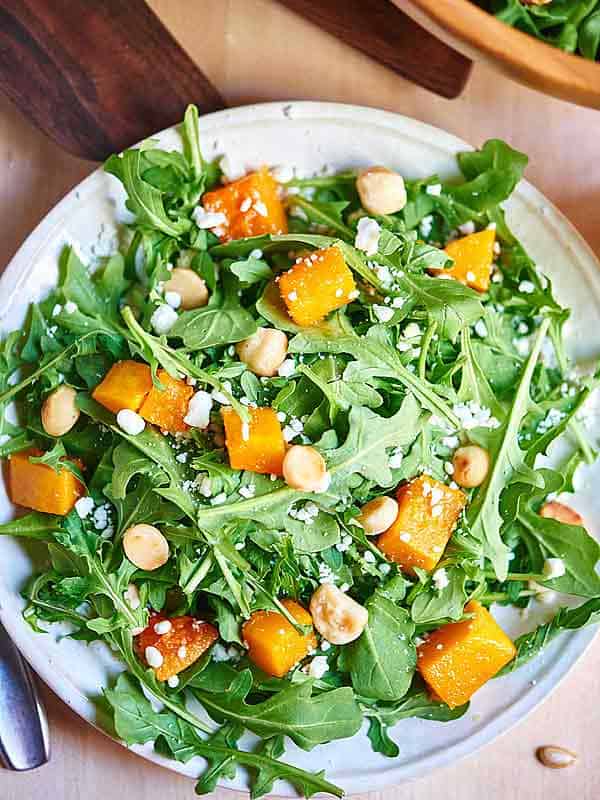 plate of roasted squash arugula salad above