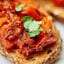 This sun dried and roma tomato bruschetta is truly flavorful and has amazing texture...I swear you won't believe it's healthy for you! I love the toasty crunch of the bread that's piled with two types of warm, juicy, tender tomatoes, spicy garlic, tangy balsamic, and sweet basil! showmetheyummy.com #bruschetta #tomato #healthy #vegan #vegetarian