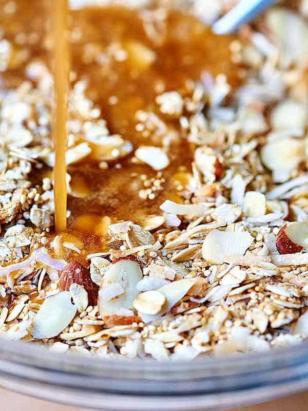 honey being drizzled into bowl of almonds, coconut, and quinoa