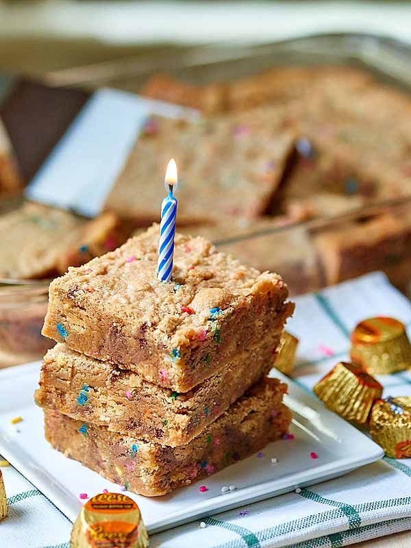 3 golden oreo peanut butter blondies stacked on plate with candle