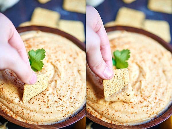 cracker being dipped into hummus