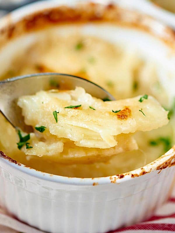 scalloped potato gratin bite being taken out of bowl with spoon