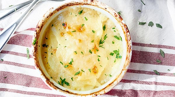 This cheesy scalloped potato gratin is simplicity at it's finest. Tender potatoes, creamy bechamel, and cheesy goodness are baked until golden brown and bubbly! showmetheyummy.com #potato #gratin #cheese #bechamel #vegetarian