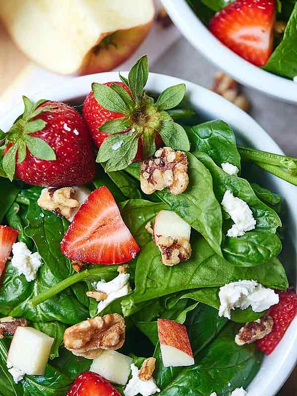 closeup of honey goat cheese spinach salad in bowl above