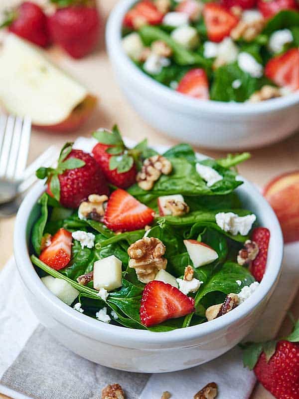 bowl of honey goat cheese strawberry spinach salad, another in background