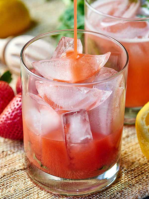 Cocktail being poured into cup with ice