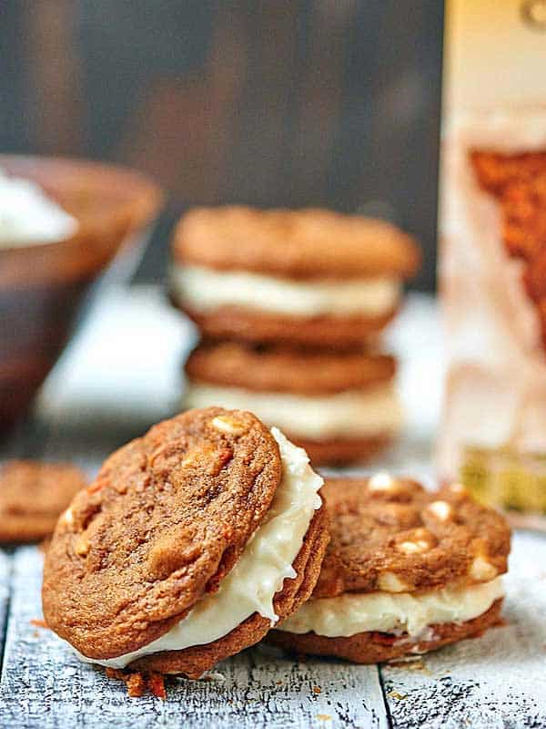 Carrot cake cookie sandwiches on cutting board one leaning on another