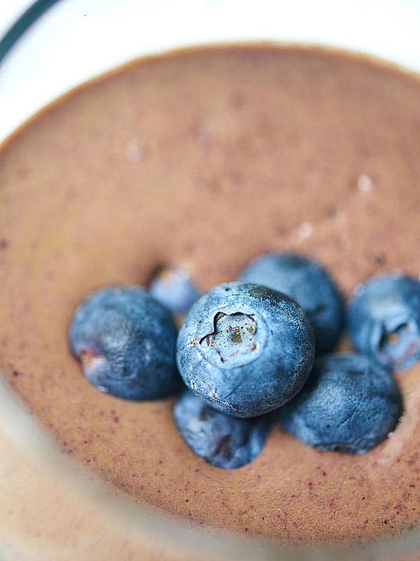 Closeup of blueberries on chocolate berry green protein smoothie