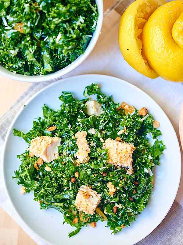 kale salad with baked almond chicken on plate above