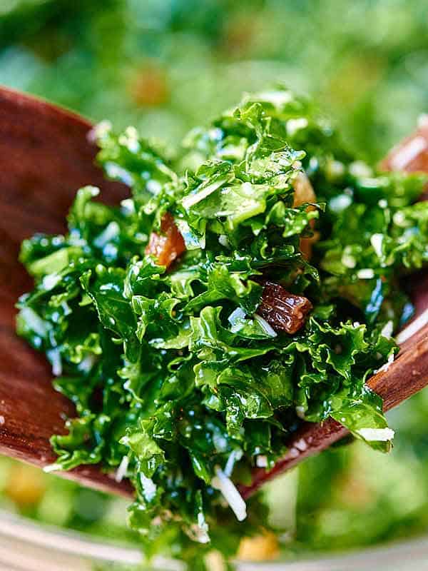 kale salad being picked up with salad tongs