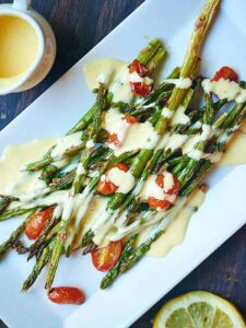 This roasted asparagus and tomato with lemon garlic hollandaise is a truly simple & elegant dish. Crisp asparagus. Juicy tomatoes. Creamy hollandaise. Yum! showmetheyummy.com #hollandaise #asparagus #tomatoes #spring #easter #vegetarian