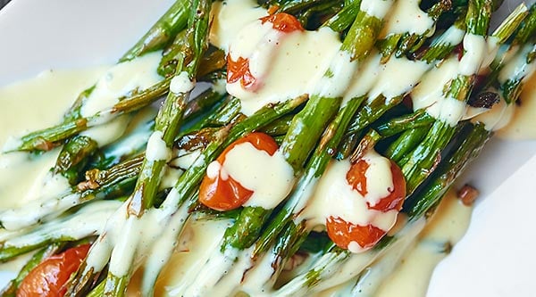This roasted asparagus and tomato with lemon garlic hollandaise is a truly simple & elegant dish. Crisp asparagus. Juicy tomatoes. Creamy hollandaise. Yum! showmetheyummy.com #hollandaise #asparagus #tomatoes #spring #easter #vegetarian
