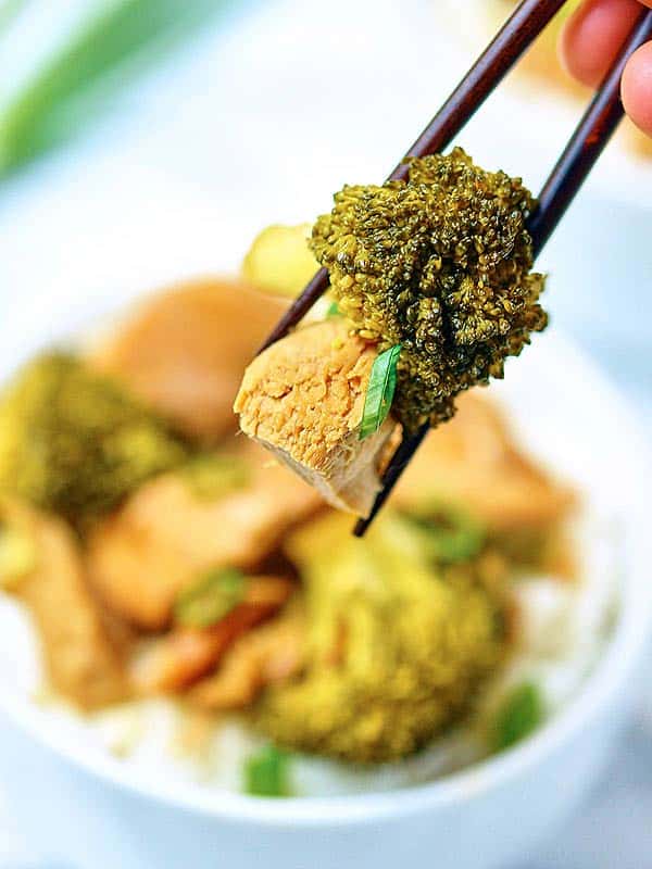 Broccoli and chicken held with chopsticks