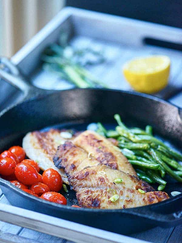 Honey, soy, and garlic tilapia in skillet from side