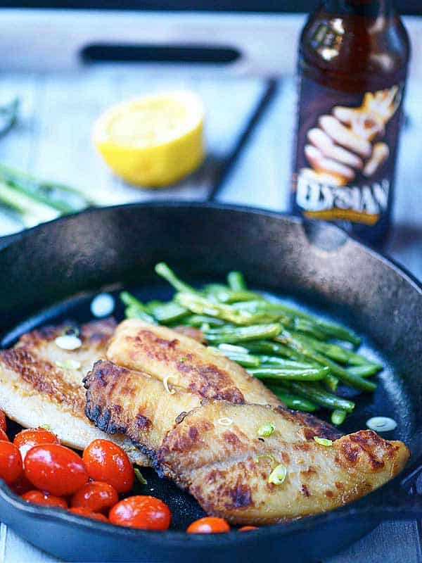 Honey, soy, and garlic tilapia in skillet with tomatoes and green beans