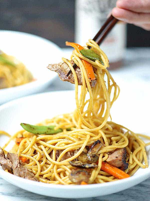 beef lo mein being picked up with chopsticks