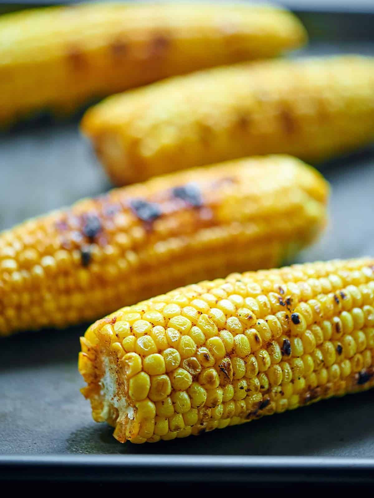 four cobs of grilled corn side view