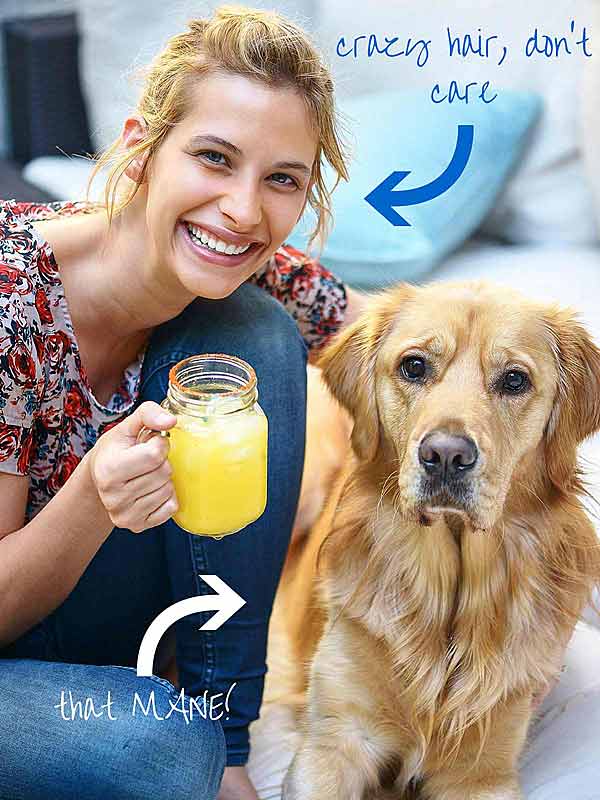 Woman holding margarita next to dog