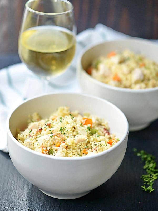 two bowls of chicken bacon couscous with glass of white wine