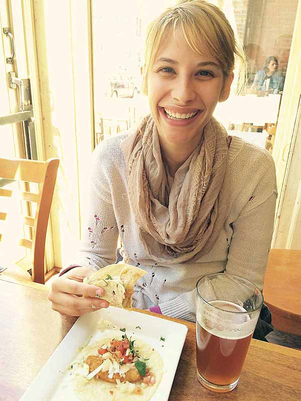 woman smiling with plate of fish tacos