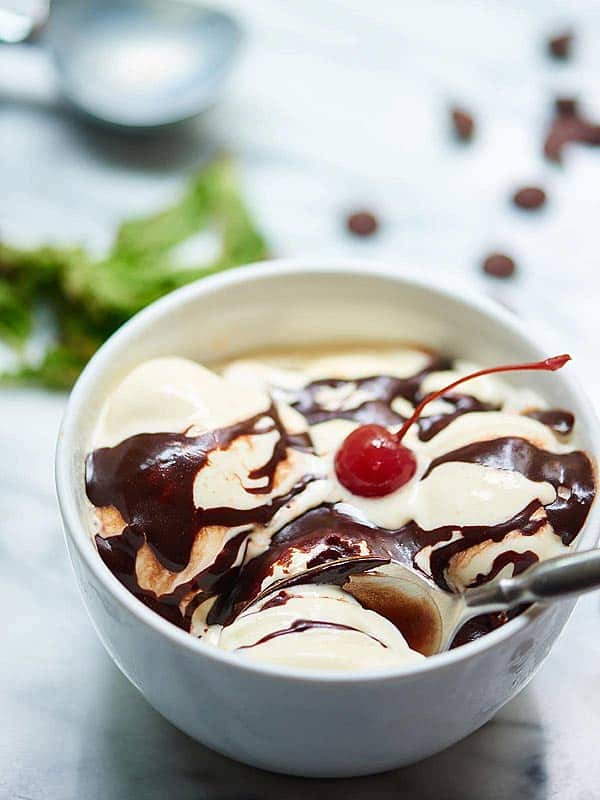 bowl of ice cream with fudge sauce and cherry