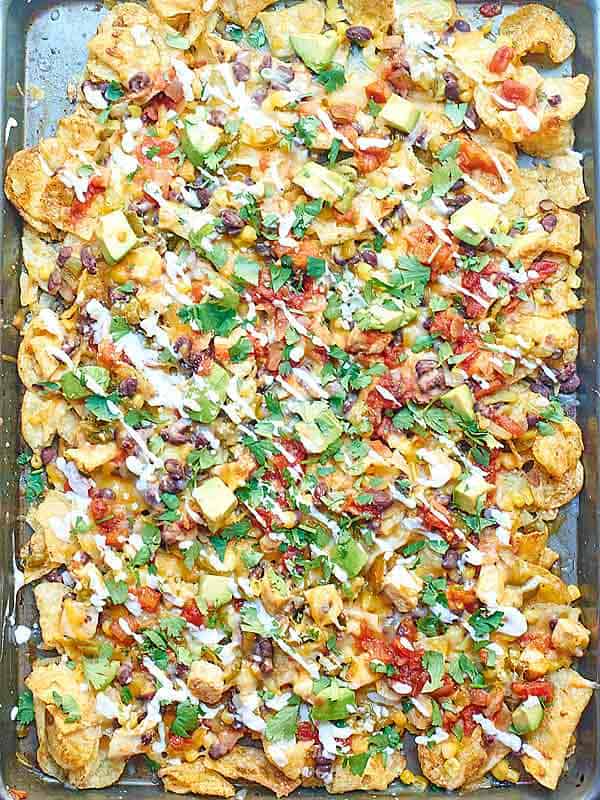 Kettle Chip Chicken Nachos. Jalapeno and Sea Salt Kettle Chips are piled with black beans, chicken, gooey cheese, sweet corn, dollops of sour cream, and some green chiles and jalapeños! showmetheyummy.com #nachos #chicken