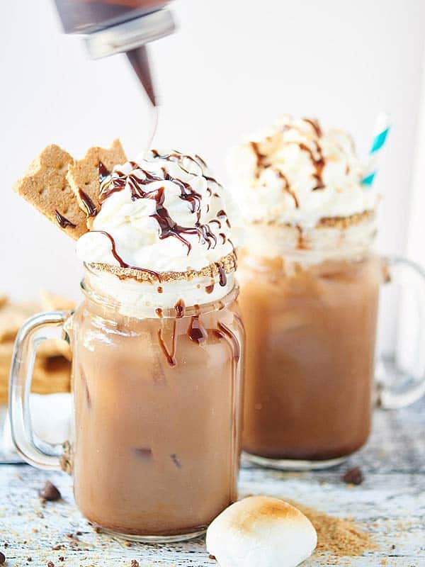 two jars of smores iced coffee with whipped cream and chocolate drizzle