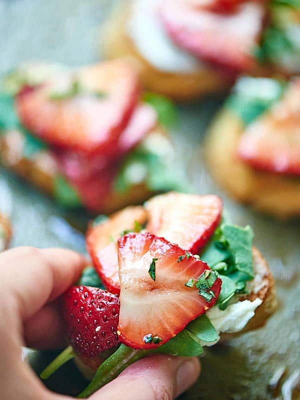 This Strawberry Goat Cheese Bruschetta is my new favorite appetizer. Slightly chewy bruschetta is topped with creamy goat cheese, peppery arugula, juicy strawberries, and earthy basil. showmetheyummy.com #bruschetta #vegetarian