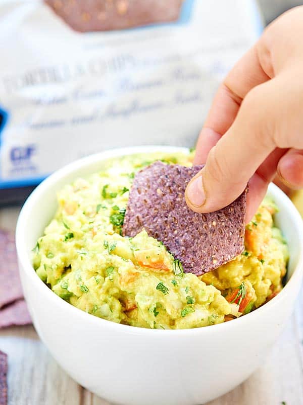 Chip being dipped into bowl of guacamole