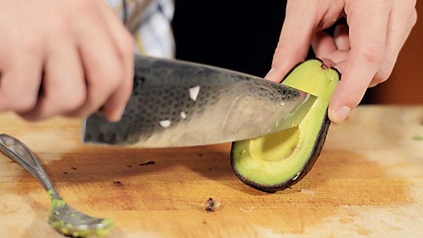 Half avocado being cut