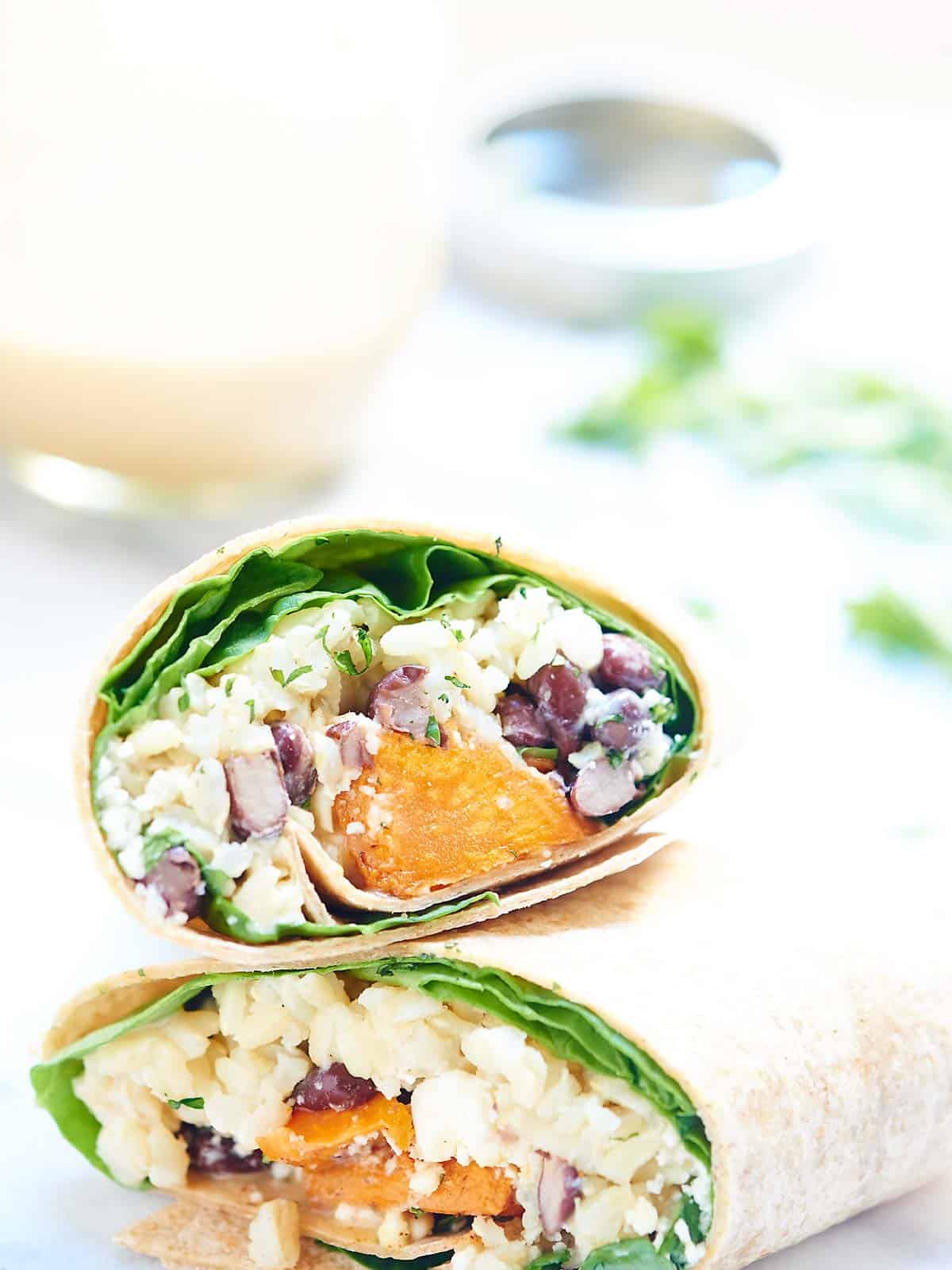This healthy sweet potato wrap is hearty, vegetarian & full of good for you ingredients like black beans, brown rice & is drizzled in a unique tahini sauce! showmetheyummy.com #wrap #vegetarian