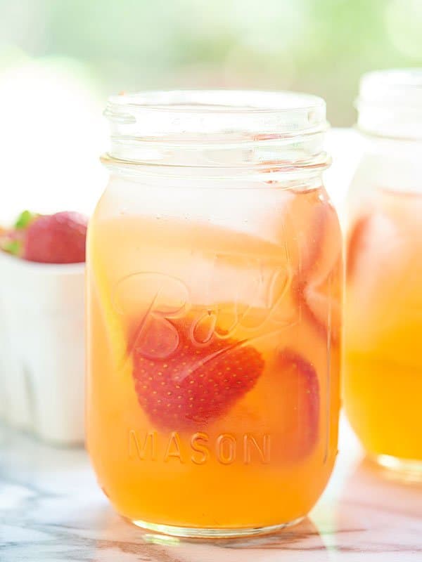 honey strawberry lemonade in a mason jar with strawberries side view