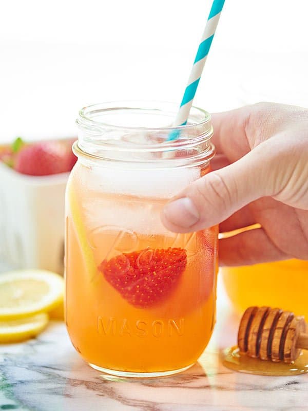 jar of honey strawberry lemonade with straw being picked up