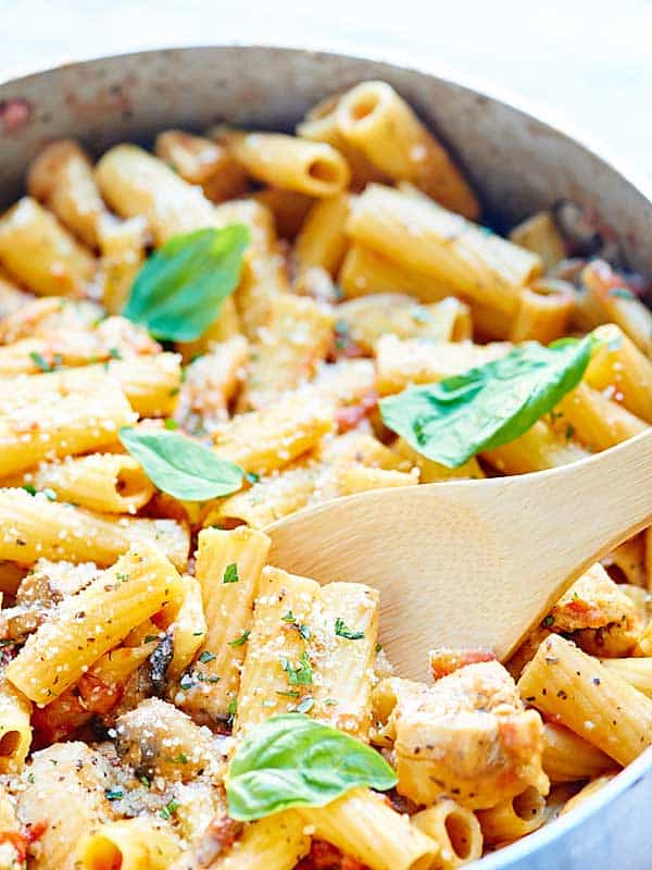 closeup of pasta in pan with wooden spoon