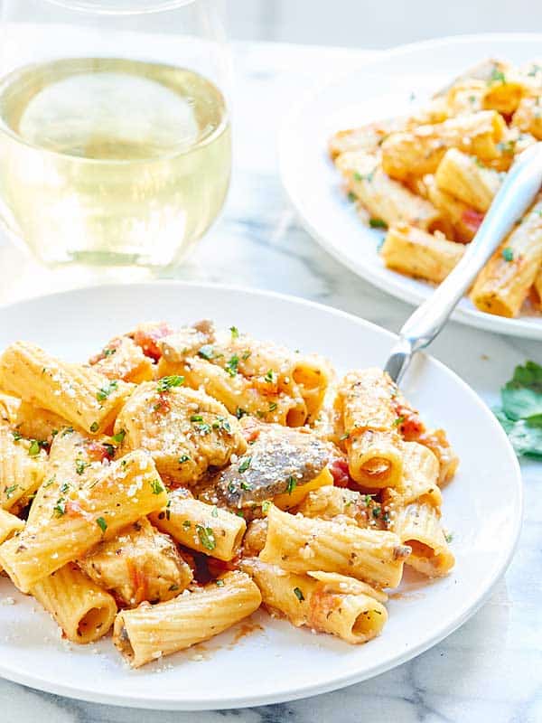 plate of one pot pasta, another behind, next to glass of wine