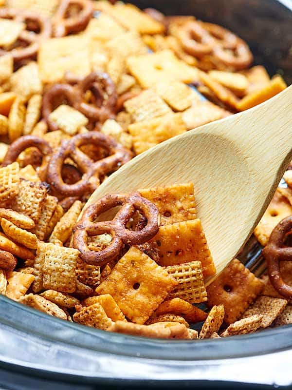 chex mix in crockpot with wooden spoon