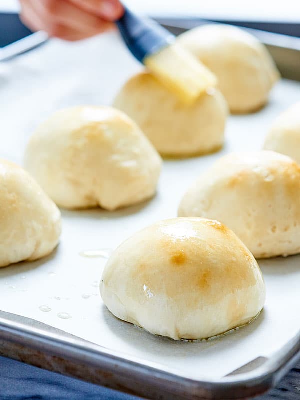 cheese bombs being basted with butter on baking sheet