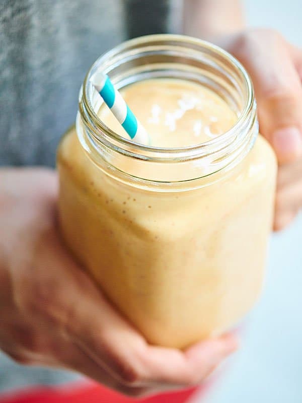 healthy peach cobbler smoothie in mason jar held above