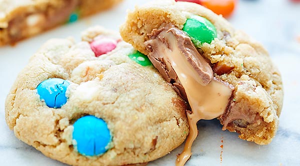 These Peanut Butter Salted Caramel Cookies are made of a simple peanut butter dough, studded with M&Ms, white chocolate chips, and salty pretzels. To make these even more decadent, they get stuffed with rolos! showmetheyummy.com #dessert #cookies