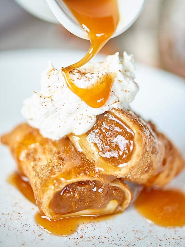 pumpkin pie egg roll on plate topped with whip and caramel