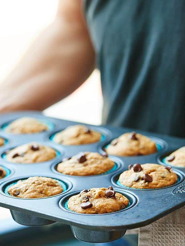 muffin tin with vegan banana chocolate chip muffins held