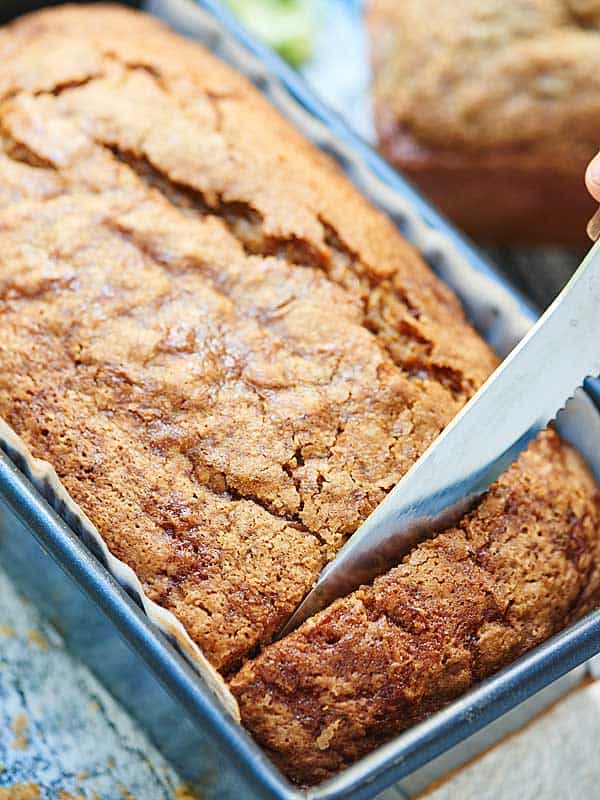 zucchini bread in loaf pan being cut